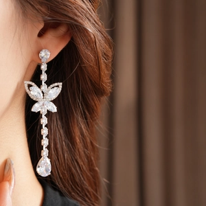 Close-up of elegant silver butterfly drop earrings with zircon crystals on a model