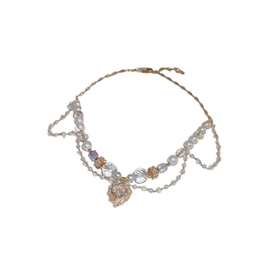 Collier multi-rangs élégant en perles et cristal avec pendentif cœur doré sur fond blanc