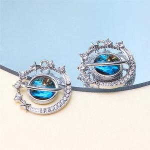 Macro shot of celestial star and planet earrings with blue starry sky inlay and reflections