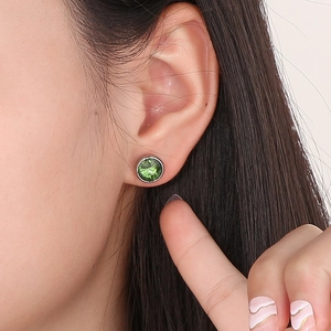 Gros plan d'une boucle d'oreille élégante en pierre verte facettée et acier titane