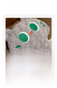 Close-up of soft grey plush cat pillow with brush-finished fur and embroidered details