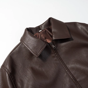 Close-up of deep brown leather jacket showing lapel structure and fine material texture