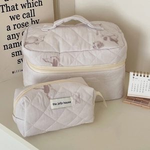 Quilted cosmetic bag set in beige fabric featuring cute puppy prints and top handle