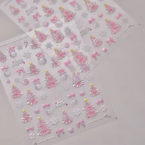 Close-up of 3D embossed Christmas nail stickers with pink trees and bow designs