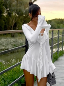 Détail d'une robe blanche à manches longues avec volants, décolleté en V et lien à l'avant