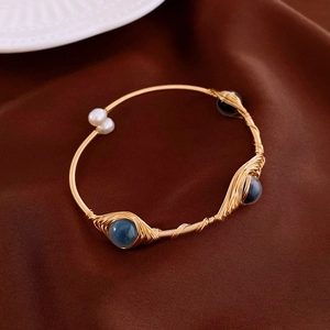 Macro shot of gold-plated wire-wrapped bracelet with freshwater pearls and blue gemstones