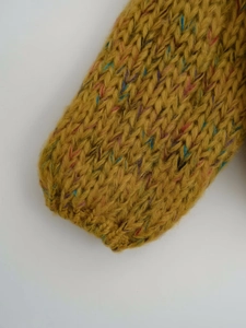 Detail of chunky ginger knit sweater cuff with colorful speckled tweed yarn fibers