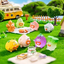 Close-up of miniature vegetable monster figures in a picnic setting on green grass
