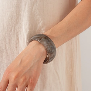 Detail of wide marble pattern resin bangle showing smooth texture and grey swirl accents