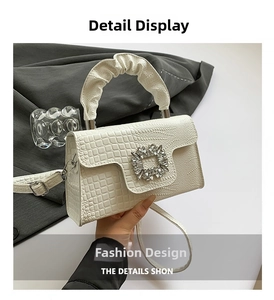 Close-up of white lizard pattern handbag featuring a large square rhinestone buckle