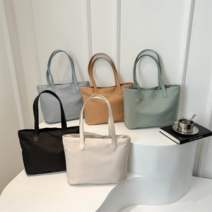 Minimalist large capacity nylon tote bags in multiple colors on white display stands
