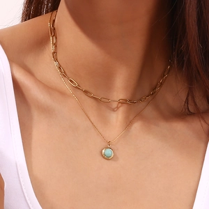 Detailed view of layered 18K gold plated paperclip chain with blue gemstone pendant on model