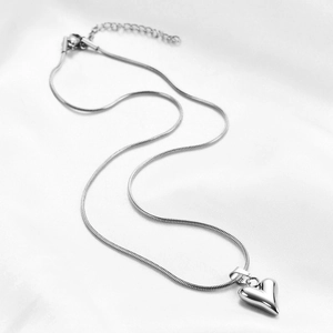 Elegant silver heart necklace with a sleek snake chain on white silk background