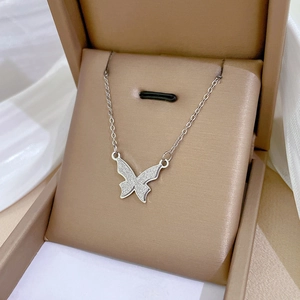 Minimalist matte butterfly pendant necklace in silver stainless steel on a brown gift box