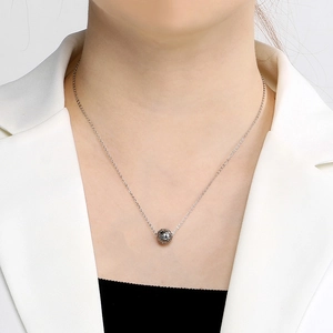 Elegant stainless steel necklace with a hollow patterned silver ball pendant worn by model
