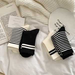 Detail of two pairs of black and white striped cotton socks on a soft knit blanket