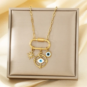 Detailed macro of gold Evil Eye necklace with star and moon charms on silk fabric