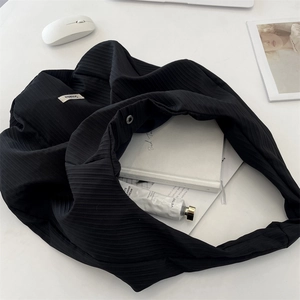 Vista detallada de un bolso tote de tela plisada negra en un ambiente minimalista