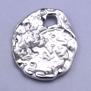 Macro shot of irregular silver oval pendant with hammer texture on grey background