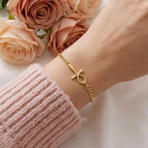 Elegant gold stainless steel Ankh cross charm bracelet worn by a woman with roses