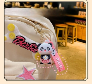 Macro detail of cute panda keychain with pink strap on a white star-patterned backpack