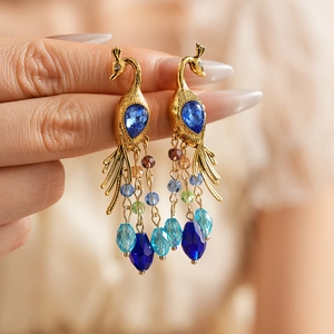 Detail of vintage peacock earrings with blue stones and colorful beaded tassel fringe