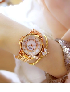 Close-up of gold chain watch for women featuring sparkling rhinestones and a pearl dial