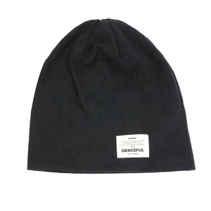 Detail of black knitted beanie featuring diamond textures and a stylish white fabric label