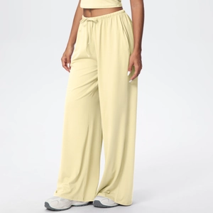 Detail of light yellow wide-leg trousers with drawstring waist and deep side pockets