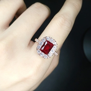 Macro shot of a rose gold ring featuring a rectangular red gemstone and halo diamonds
