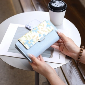 Close-up of light blue floral print long wallet with a golden metal snap closure