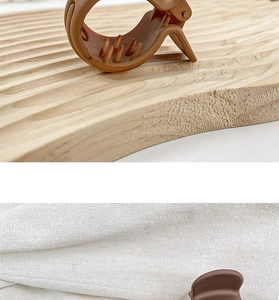 Detail of brown claw clip on wooden tray and linen cloth showing hair grip teeth