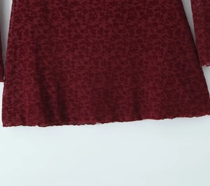 Detail of burgundy floral lace fabric showing intricate patterns and sheer texture