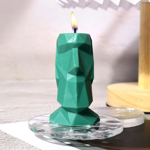 Detailopname van een brandende groene Moai-kaars met abstract geometrisch ontwerp