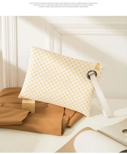 Detail view of white crocodile pattern clutch with yellow motifs and leather strap