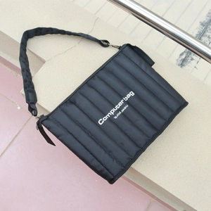 Macro view of black quilted laptop bag with striped texture and woven shoulder strap