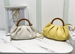 Detail of soft pleated cloud bags with vintage wooden round handles and gold chain straps