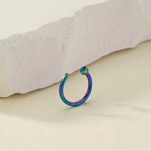 Close-up of rainbow non-pierced nose ring with flat-head stud on a textured stone surface