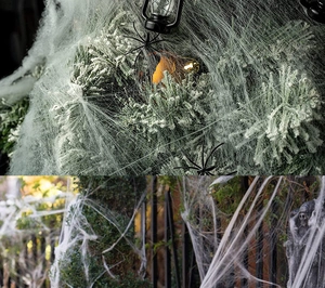 Outdoor Halloween decor with white spider web on plants and fence with lanterns