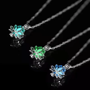 Luminous lotus locket necklace set with blue and green glow on reflective surface