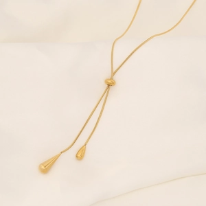 Detail of a golden water drop tassel necklace in a Y-shaped snake chain design