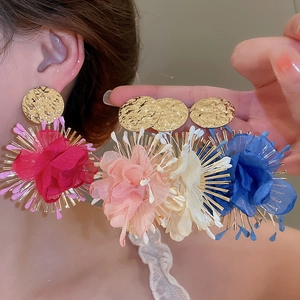 Detailed close-up of large chiffon flower earrings in red, pink, white, and blue colors
