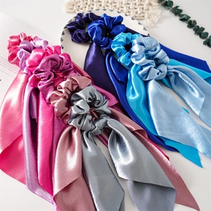 Detail of satin scrunchie with long ribbons in multiple vibrant colors on white background
