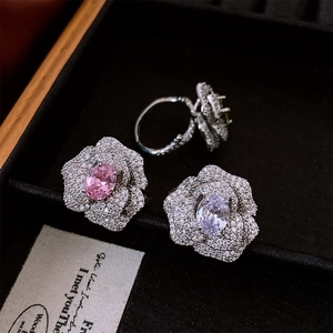 Macro shot of silver camellia flower rings with pink and white zircon in velvet box