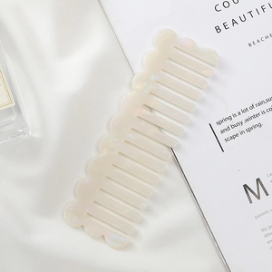 Detail of a beige acetate hair comb with marble texture on elegant white silk background
