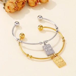 Detail of gold and silver steel open bangles with engraved lucky square pendants