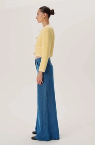 Side view of high-waisted wide-leg jeans paired with a yellow tweed jacket on a model