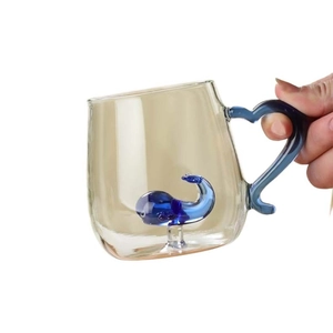 Creative whale glass mug with amber gradient and blue heart handle held in hand