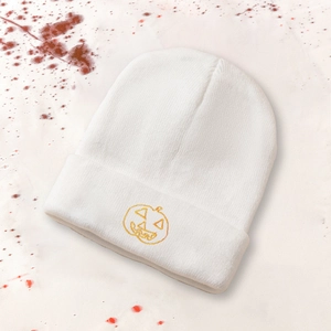 White knit beanie with pumpkin embroidery and spooky red paint splatter background