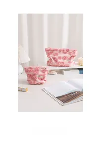 Détail de deux trousses de maquillage en peluche rose avec fleurs 3D en deux tailles